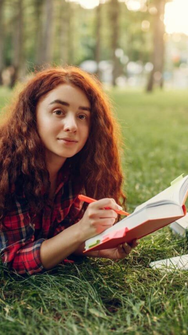 Female student preparing for exams on the grass